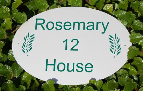 White oval house sign with green lettering