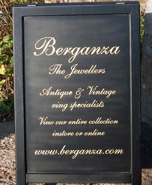 A black painted sandwich board with gold painted lettering. Blacked Painted Sandwich Board